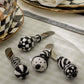 Set of four black and white checkered ceramic cheese knives on a light surface.